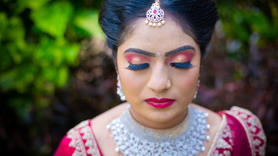Beautiful Udaipur bride with flawless bridal makeup and traditional jewelry posing against heritage palace backdrop