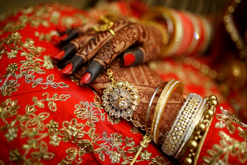 Bride getting intricate henna designs applied during mehndi ceremony with traditional decorations